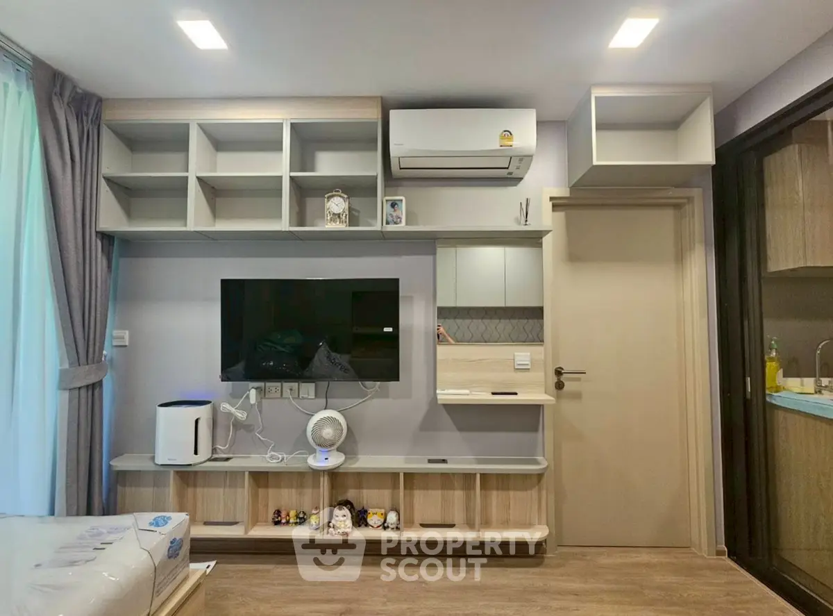 Modern living room with built-in shelves, air conditioning, and sleek TV setup in a cozy apartment.