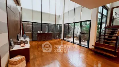 Spacious living room with wooden flooring and large windows opening to a private garden patio.