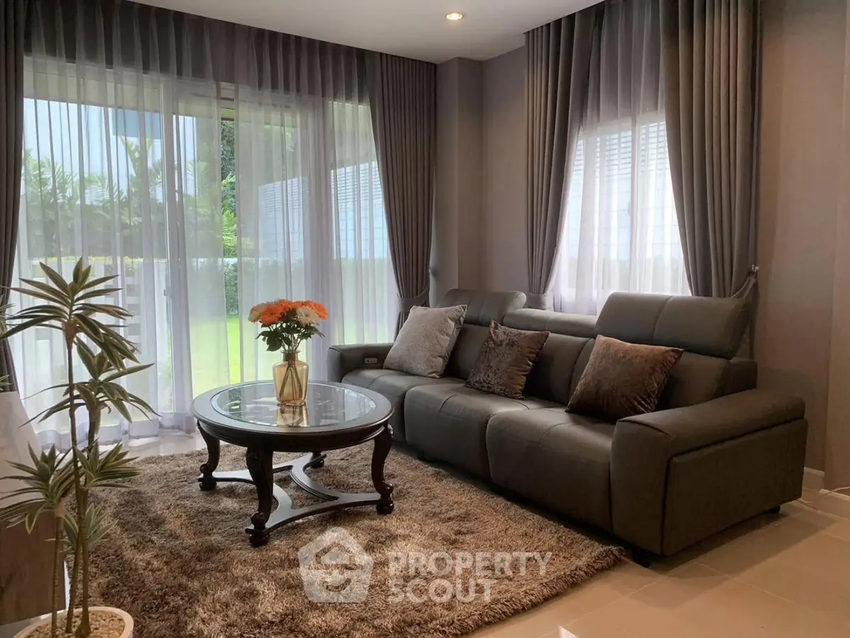Elegant living room with plush sofa, stylish curtains, and garden view, perfect for relaxation.