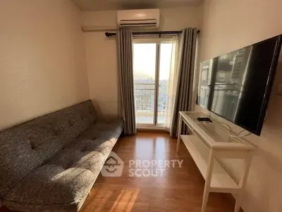 Cozy living room with modern sofa, wall-mounted TV, and large window offering natural light.
