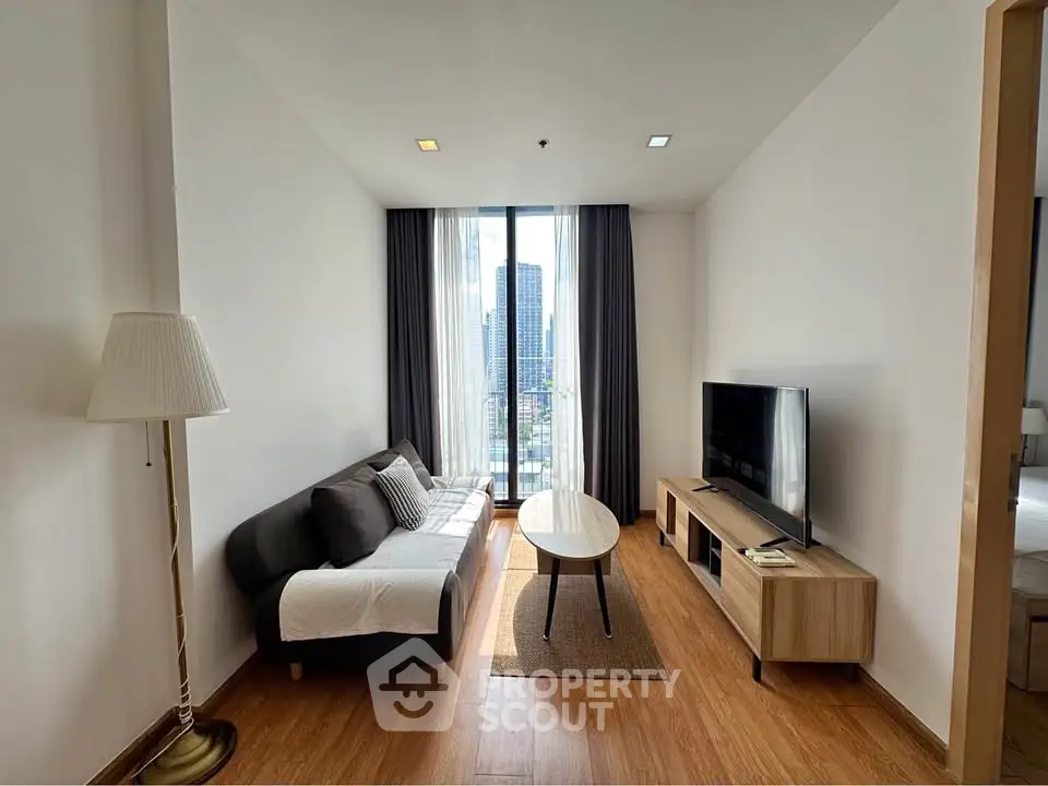 Modern living room with city view, featuring sleek furniture and large windows for natural light.