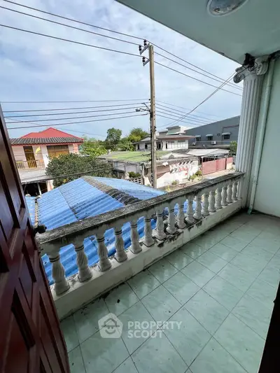 Charming balcony with classic balustrade offering neighborhood views and open sky.