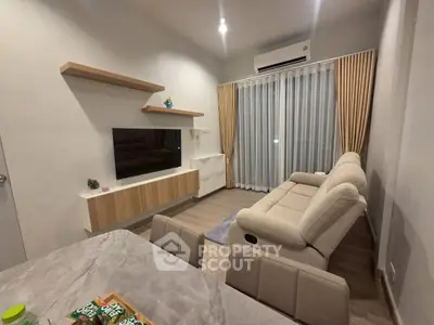 Modern living room with cozy sofa, wall-mounted TV, and elegant curtains