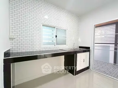 Modern minimalist kitchen with sleek black countertops and white subway tile backsplash.