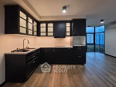 Modern kitchen with sleek black cabinets and open layout in high-rise apartment.