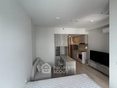 Modern studio apartment with open layout, featuring a cozy living area, sleek kitchen, and comfortable bed.