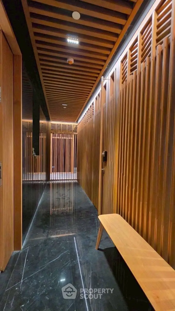 Luxurious modern building corridor with sleek wooden paneling and elegant black marble flooring.