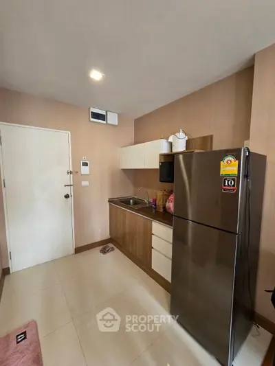Modern kitchen with sleek cabinetry and stainless steel fridge in a cozy apartment.