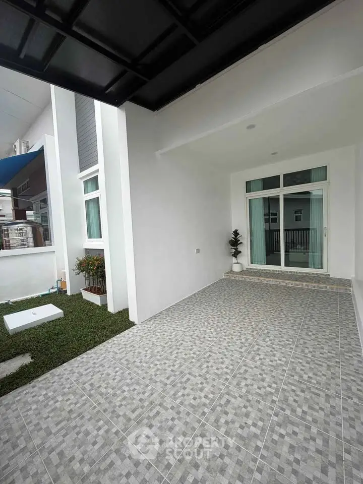 Modern exterior with tiled patio and sliding glass doors in a contemporary home.