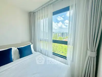 Bright bedroom with large window offering stunning city view and elegant white curtains.