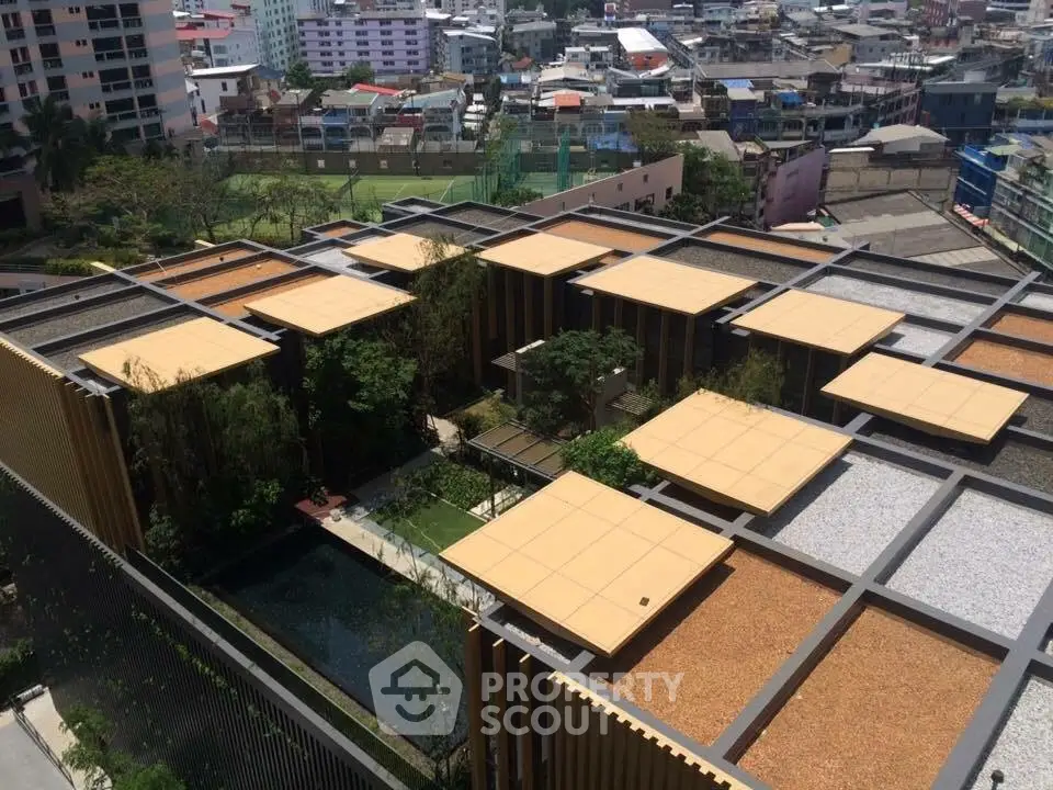 Stunning aerial view of modern building with rooftop garden and cityscape backdrop.