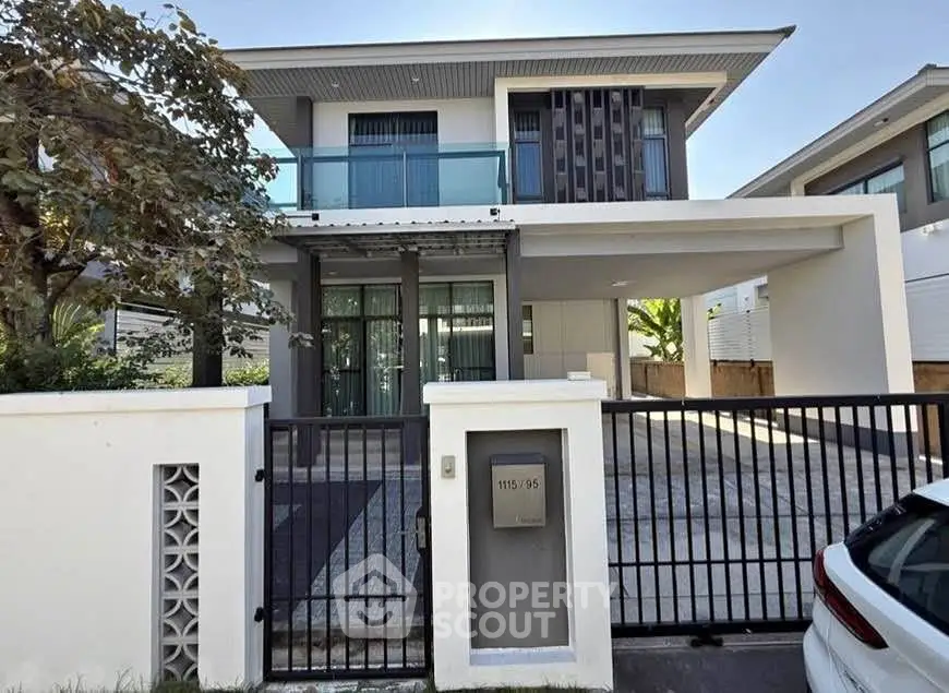 Modern two-story house with sleek design and gated driveway in a suburban neighborhood.