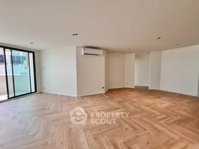 Spacious modern living room with herringbone wood flooring and large windows.