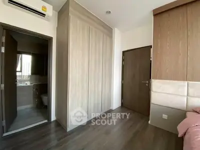 Modern bedroom with wooden flooring and built-in wardrobe, featuring a sleek air conditioning unit.
