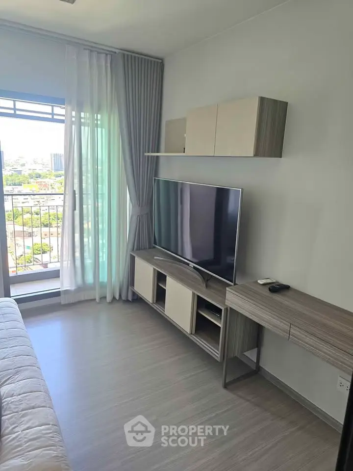 Modern living room with sleek TV setup and balcony view in stylish apartment.
