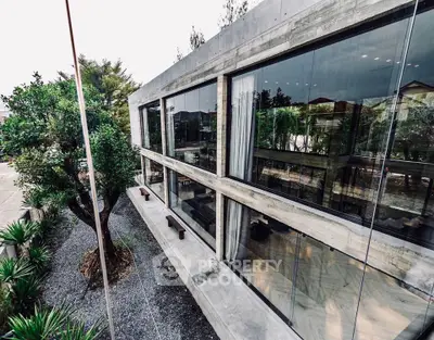 Modern architectural home with large glass windows and lush greenery