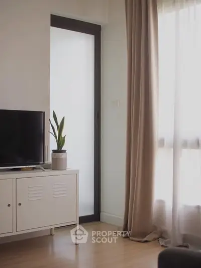 Cozy living room with TV and elegant curtains, perfect for relaxation.