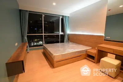 Modern bedroom with large window and city view, featuring stylish wooden furniture and ambient lighting.