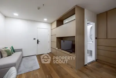 Modern living room with wooden flooring and built-in TV unit, adjacent to a compact bathroom.