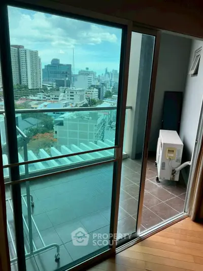 Modern apartment balcony with city view and sliding glass doors.