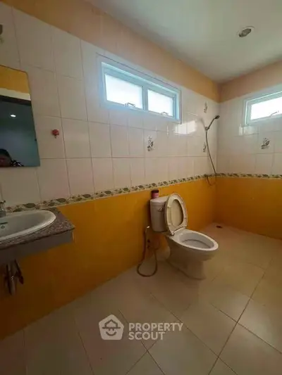 Spacious bathroom with modern fixtures and natural light from high windows.