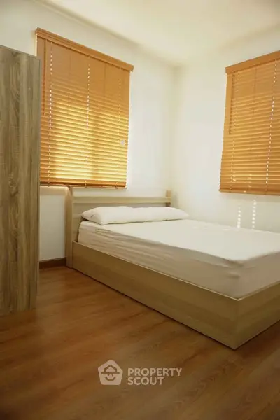 Cozy bedroom with wooden flooring and blinds, perfect for relaxation.
