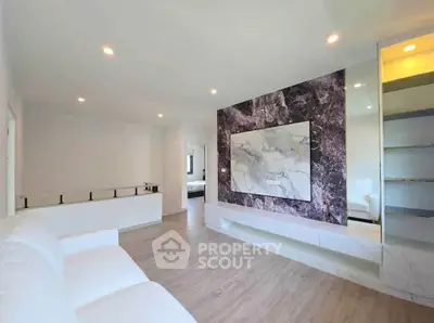 Spacious modern living room with elegant marble feature wall and sleek wooden flooring.