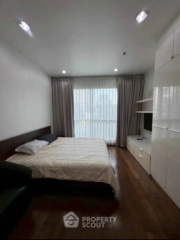 Modern bedroom with wooden flooring and large window for natural light