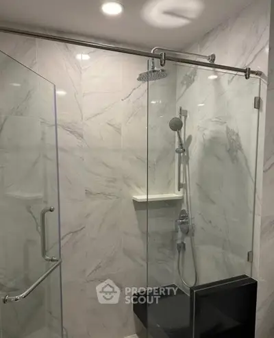 Modern bathroom with glass shower enclosure and marble tiles