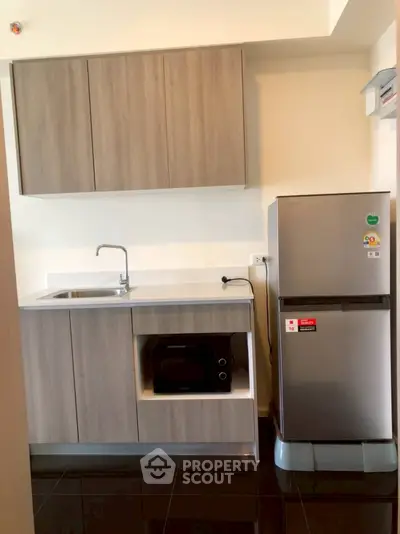 Modern kitchen with sleek cabinetry and stainless steel fridge in compact layout.