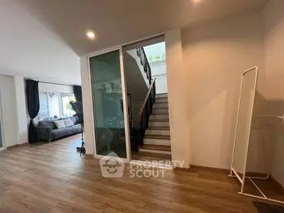 Spacious modern living area with wooden flooring and staircase, perfect for family gatherings.