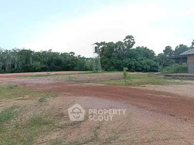 Expansive land plot with lush greenery and a watchtower, ideal for development opportunities.
