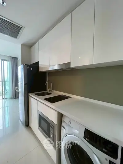 Modern kitchen with sleek appliances and ample storage in a stylish apartment.