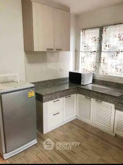 Modern kitchen with granite countertops and compact appliances in a cozy apartment.