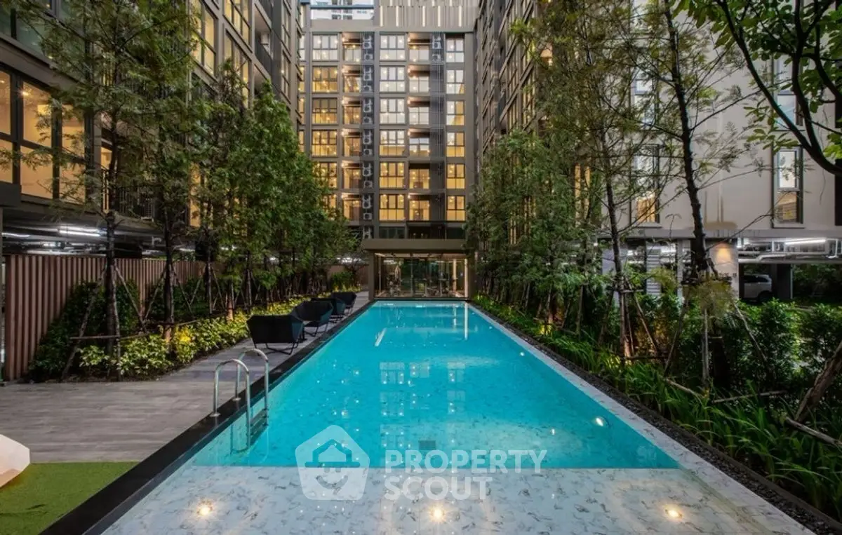 Luxurious modern apartment complex with stunning outdoor pool and lush greenery.