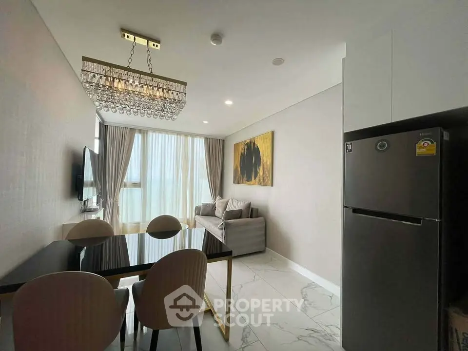 Modern living room with elegant chandelier and dining area in a stylish apartment.