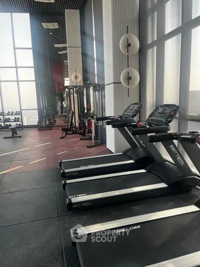 Modern gym with treadmills and weightlifting equipment in high-rise building