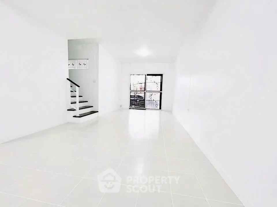 Spacious white interior with staircase and large window, perfect for modern living.