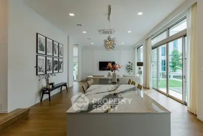 Luxurious open-plan living room with modern decor and large windows overlooking greenery.