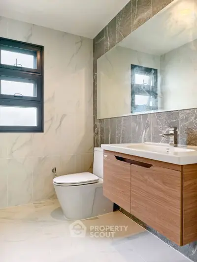 Modern bathroom with elegant marble tiles and sleek wooden vanity.