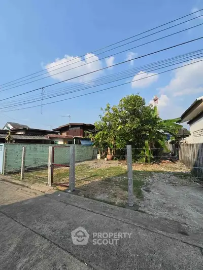 Vacant land plot with potential for development in a residential area, featuring clear skies and surrounding homes.