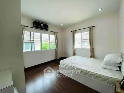 Spacious bedroom with large windows and wooden flooring in a modern home.