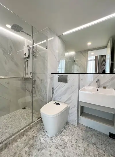 Modern bathroom with sleek design, featuring a glass shower enclosure and contemporary fixtures.