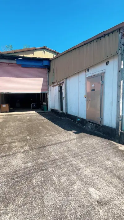Industrial warehouse exterior with loading dock and metal doors under clear blue sky.