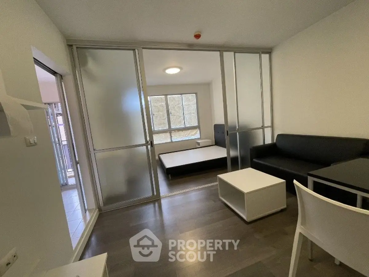 Modern studio apartment with sliding glass doors and minimalist furniture.