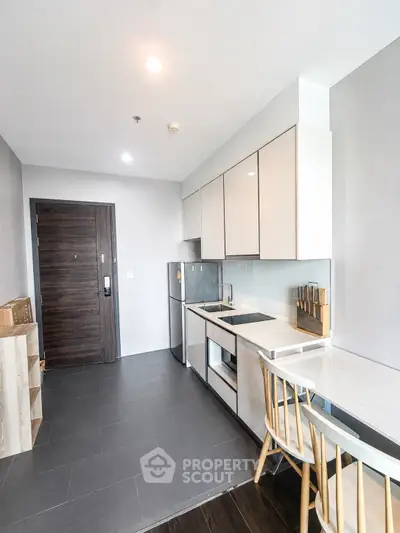 Modern kitchen with sleek cabinetry and dining area in contemporary apartment