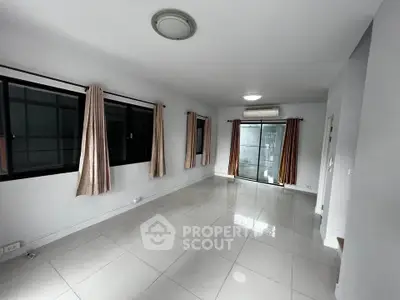 Spacious empty living room with large windows and tiled flooring