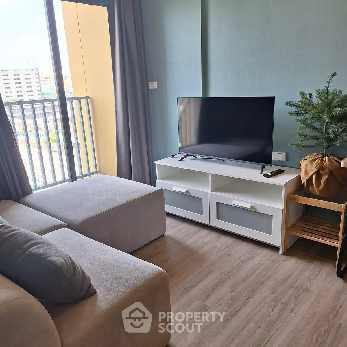 Modern living room with sleek TV stand and cozy sofa, featuring a large window with city view.
