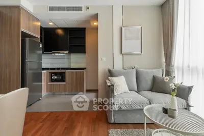 Modern living room with open kitchen and cozy sofa, featuring sleek design and natural light.