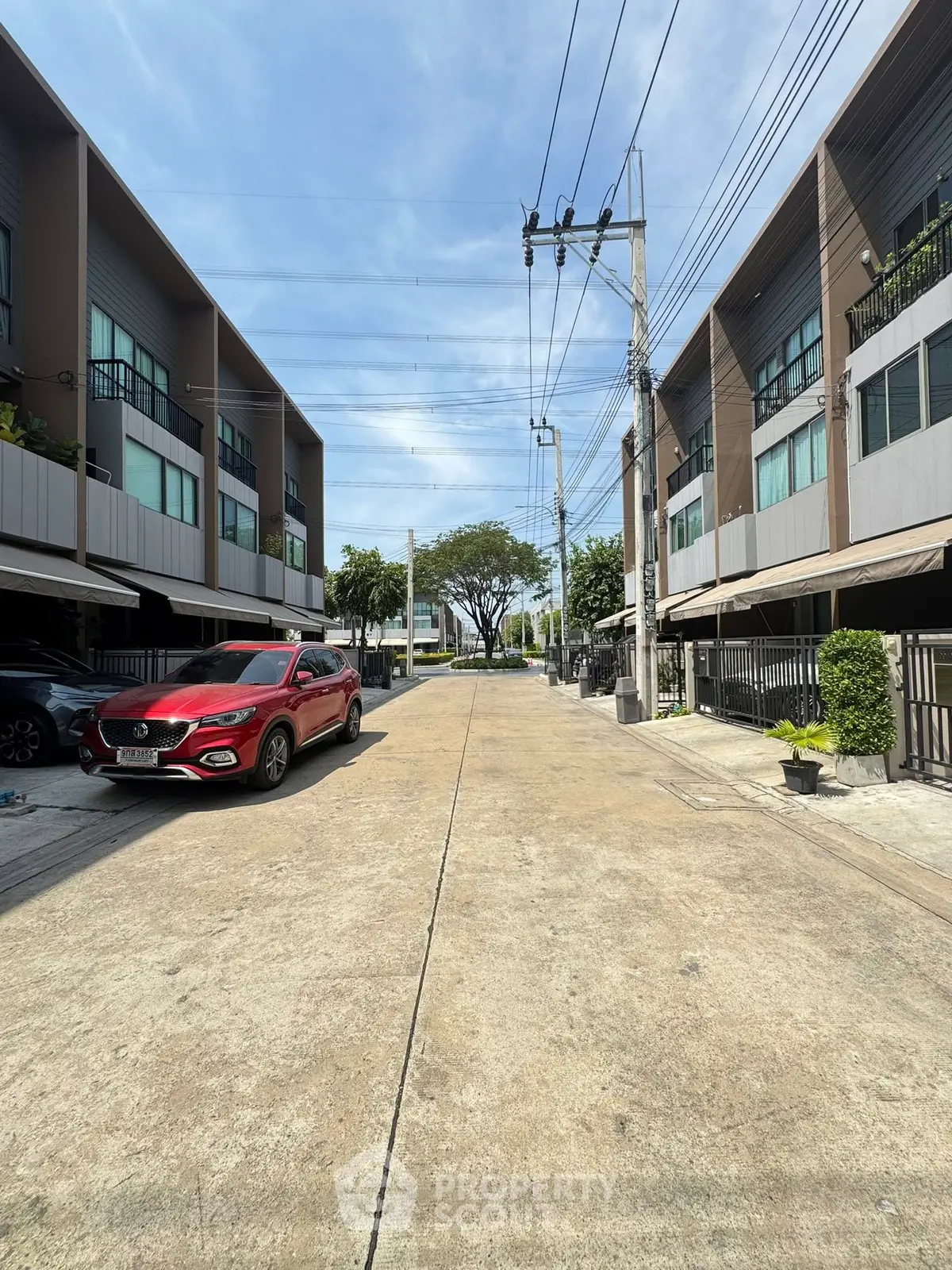Modern townhouse complex with parked cars and clear blue sky, showcasing urban living.